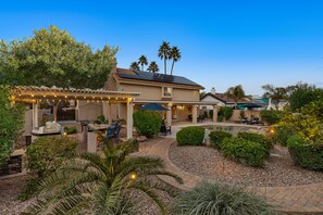 A residential property with a patio area, outdoor seating, and a swimming pool.