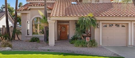 A single-story house with a tiled roof, a front door, and a garage.