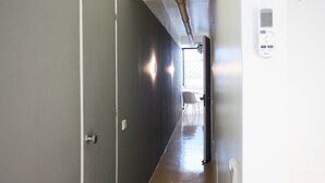 Un pasillo con una puerta, un radiador y un termostato fijado a la pared.