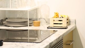 Una cocina con encimera de mármol, cafetera y frutera.
