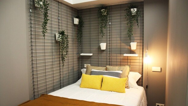 Un dormitorio con una cama, un edredón marrón, un almohadón blanco y un almohadón amarillo.