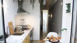 Una cocina moderna con encimera de mármol, un fregadero y un comedor con una mesa dispuesta para el desayuno.