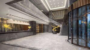 Een ruime lobby met een marmeren vloer, een centraal spiraaltrap en een receptiehoek met een modern design.