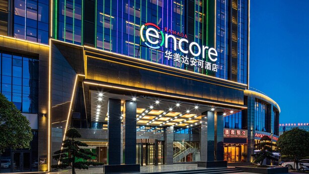 Een modern hotel met een opvallende ingang, grote ramen en een goed verlichte gevel.