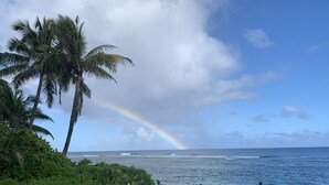 A coastal view with palm trees, a rainbow, and the ocean. - Oceanfront condo with stunning views. Oahu’s last best kept secret (Waianae)