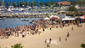 A crowded beach with people, boats, and tents.
