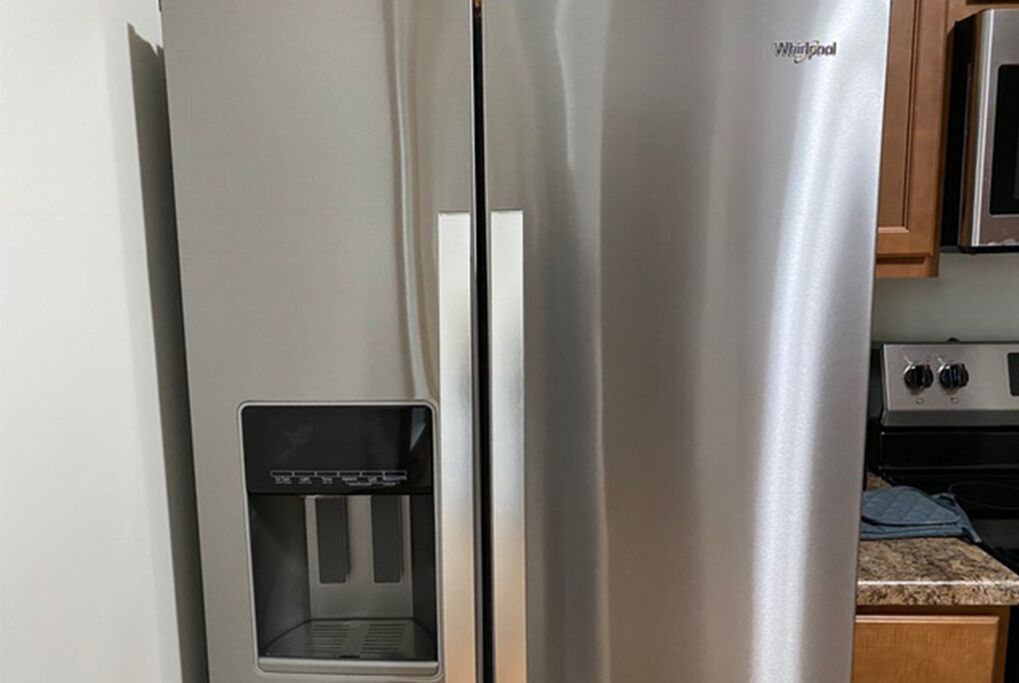 A stainless steel Whirlpool refrigerator with a water dispenser.