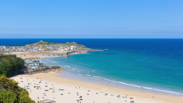 A coastal town with a sandy beach, a bridge, and buildings along the shore.