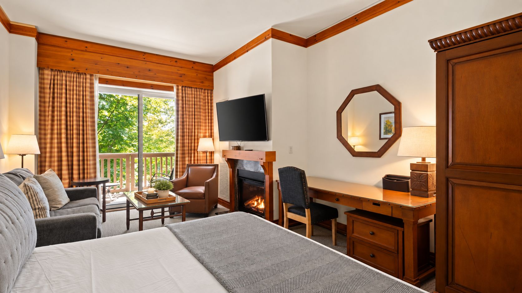 Ein Hotelzimmer mit einem Bett, einem Schreibtisch, einem Sessel, einem Fernseher und einem Kamin.