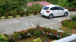 A white car parked on a road with a red roof house in the background. - Apartment COLIBRI (Saint-Esprit)