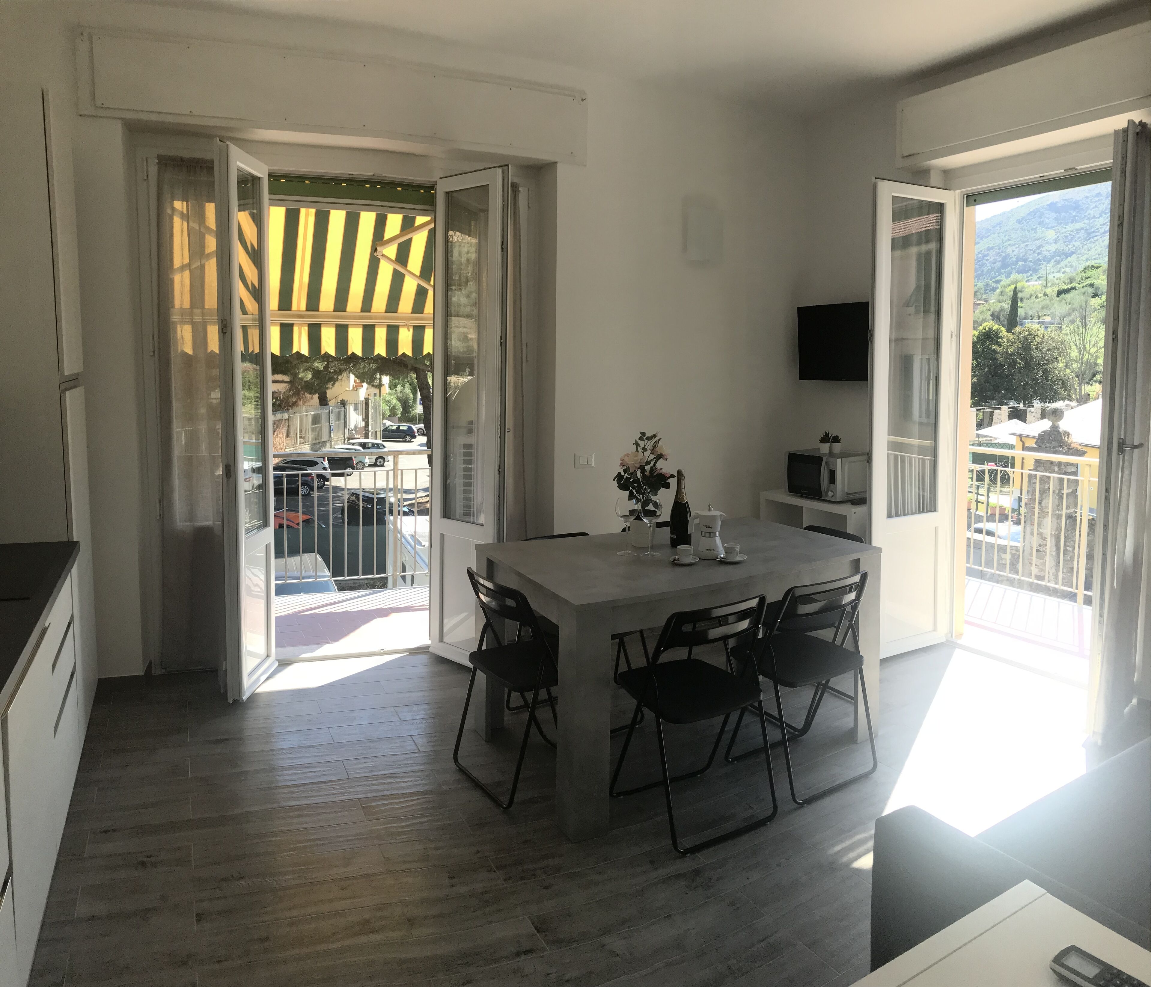 A modern kitchen with a dining area, large windows, and a view of the street.