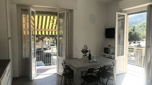 A modern kitchen with a dining area, large windows, and a view of the street. - Sant'antonino Apartments - Maestrale (levanto)