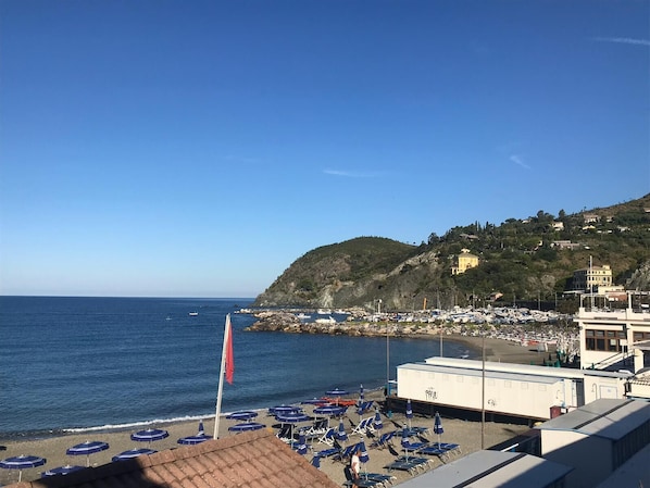 Enjoy a serene beach experience with lounge chairs and umbrellas, surrounded by a picturesque hilly landscape and calm sea.