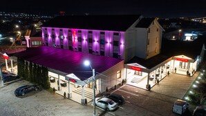A hotel with a purple-lit facade, a parking lot, and a gas station. - Hotel Polaris (Scheia)