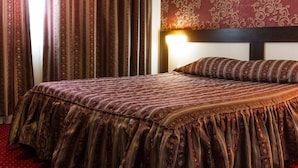 A hotel room with a large bed, a headboard with a light fixture, and a patterned wall. - Hotel Polaris (Scheia)
