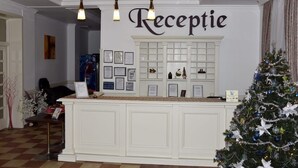 A reception area with a white reception desk, framed certificates on the wall, and a Christmas tree. - Hotel Polaris (Scheia)