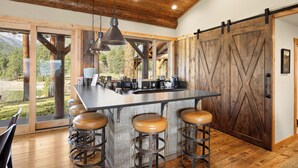 A kitchen with a large island, bar stools, and a sliding barn-style door.