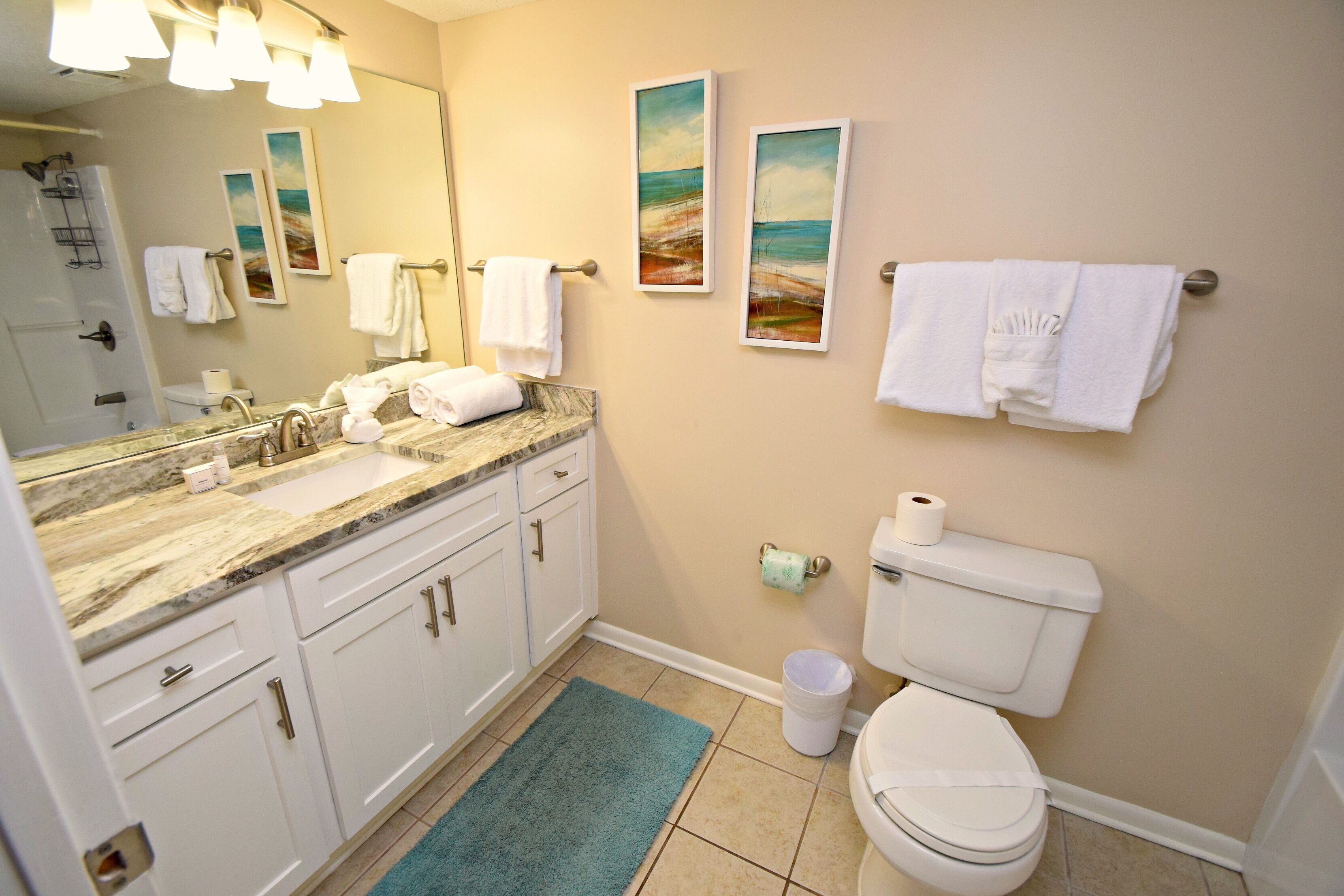 A bathroom with a sink, mirror, toilet, and towels.