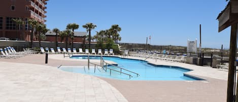 A swimming pool area with multiple pools, lounge chairs, and palm trees.