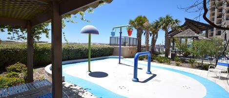 A pool area with a blue water slide, a sunshade, and a seating area with blue loungers.