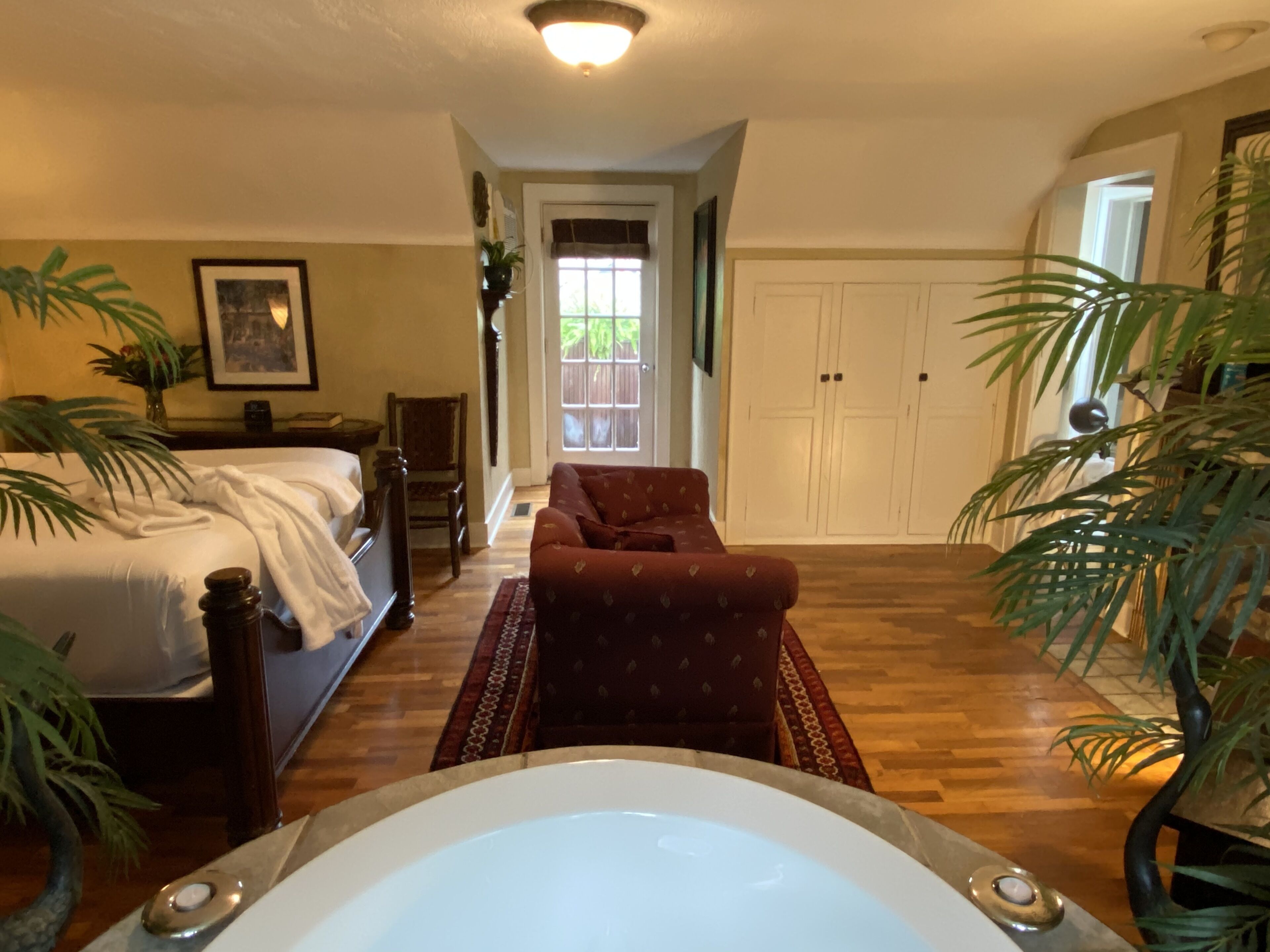 Une chambre avec un grand lit, une chaise, une baignoire et une porte donnant sur un placard.