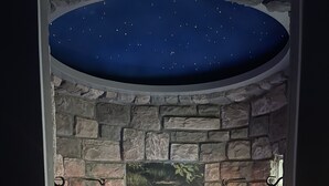 A spa area with a stone wall, a mural of a pond, and two lanterns. - Wild Goose Inn (East Lansing)