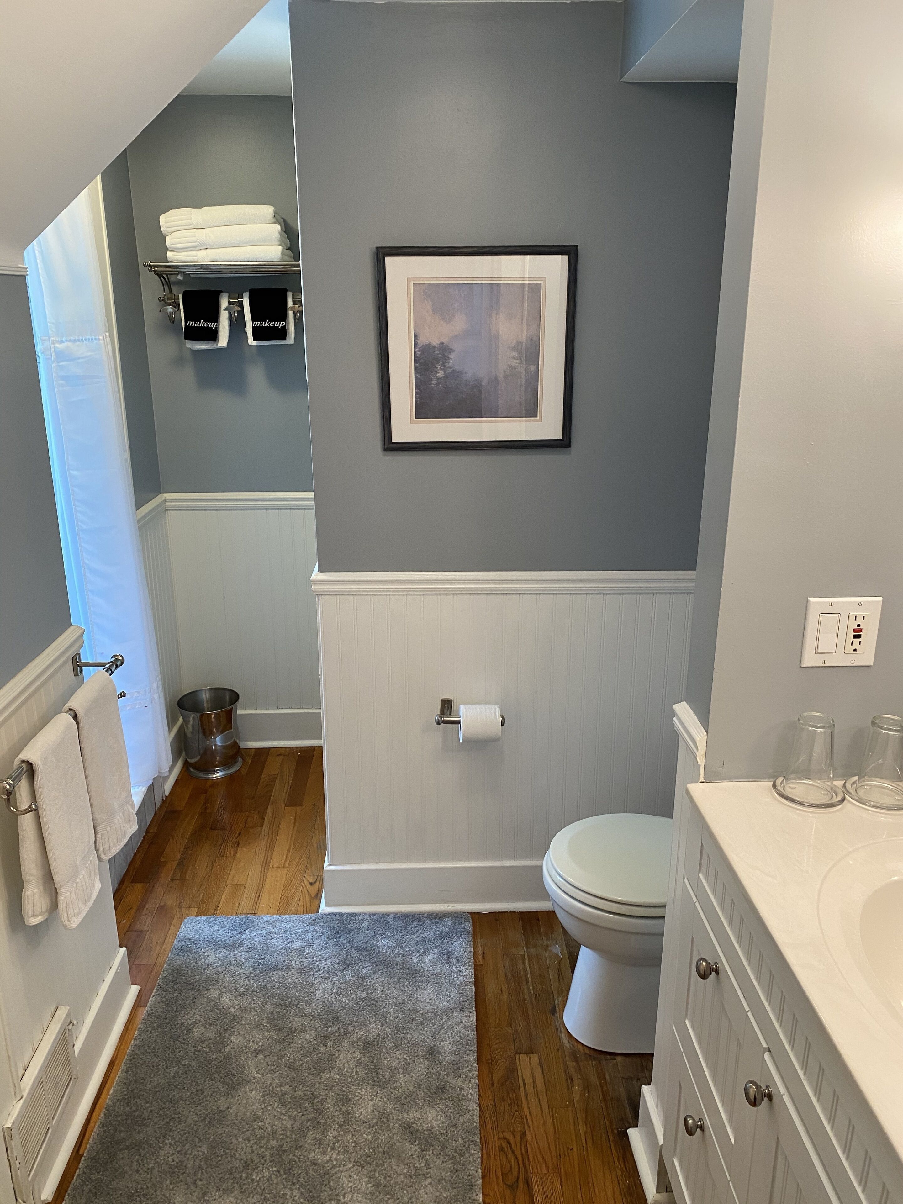 A bathroom with a toilet, sink, and framed picture on the wall.
