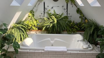 Un baño moderno con una bañera independiente, tragaluces y diversas plantas.