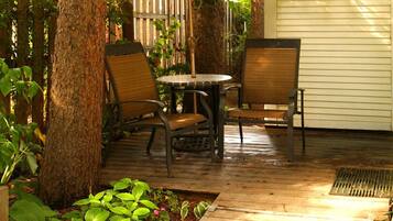 A patio area with a table and chairs, surrounded by plants and trees.