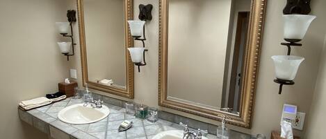Un baño con dos lavamanos, espejos amplios y un tragaluz.
