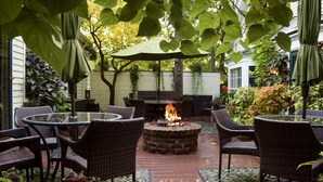 A patio with wicker furniture, a fire pit, and green umbrellas. - Wild Goose Inn (East Lansing)