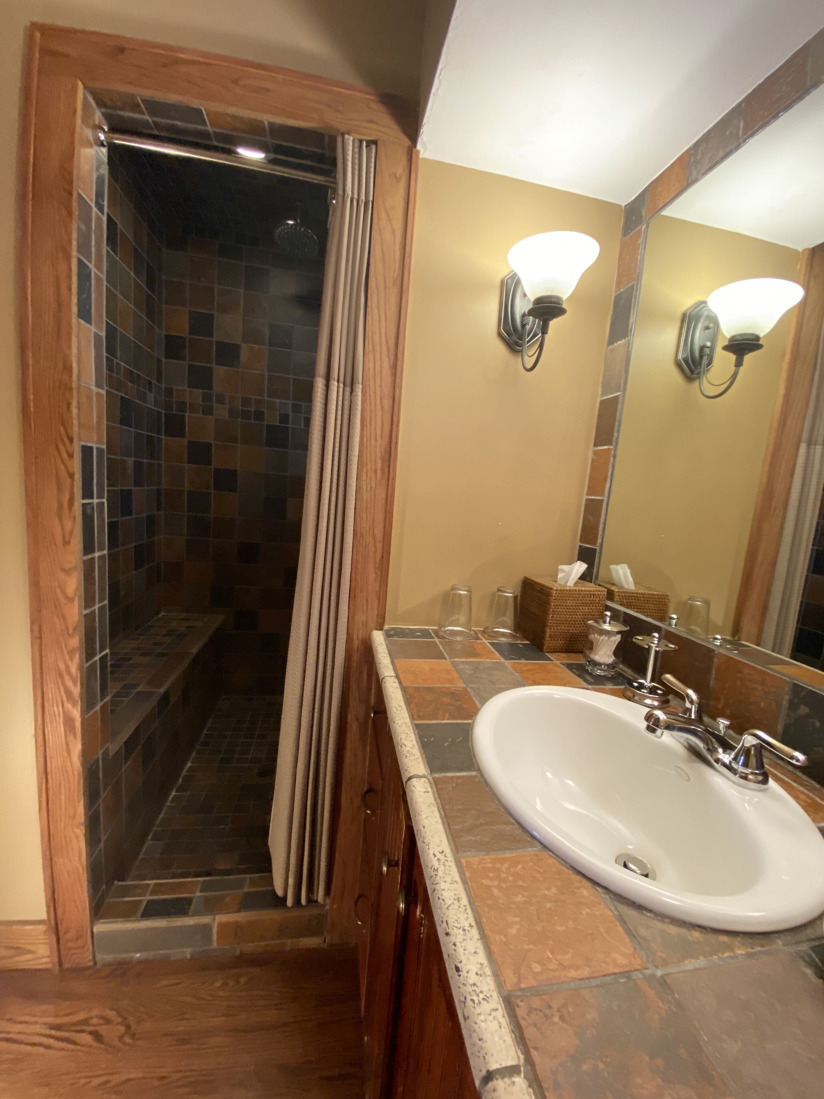 A bathroom with a shower, a sink, and a mirror.