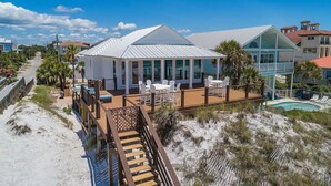 A beachfront property with a covered patio, outdoor seating, and a pool.