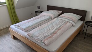 A single bed with a wooden frame, two bedside tables, a lamp, and a window with curtains. - Vacations in the historic city center of Zittau - IO19 / 2R (Zittau)