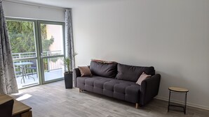 A modern living room with a grey sofa, a small round table, and a potted plant. - Vacations in the historic city center of Zittau - IO19 / 2R (Zittau)