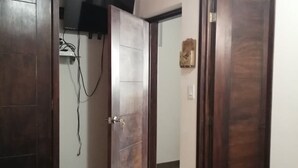 Un dormitorio con cama, armario de madera y espejo.