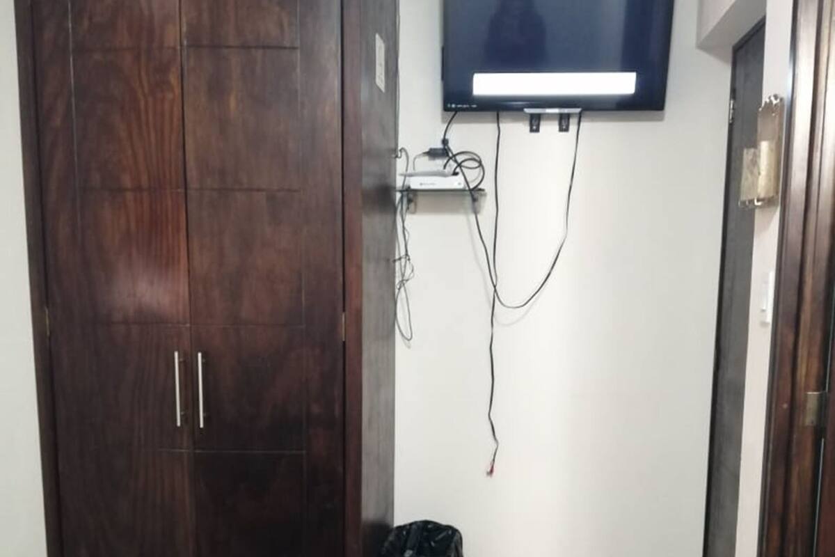 A bedroom with a bed, a wardrobe, and a television mounted on the wall.