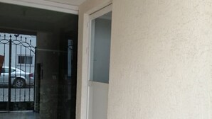 Habitación con puerta corredera de vidrio que da a un balcón, piso de baldosas y pared blanca con textura.