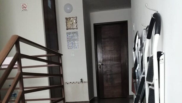 Una escalera con barandilla de madera que conduce a una puerta de madera oscura.