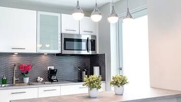 A modern kitchen with white cabinets, a built-in microwave, and pendant lighting.
