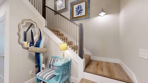 Un escalier avec des finitions en bois, une chaise bleue, une petite table et une lampe.