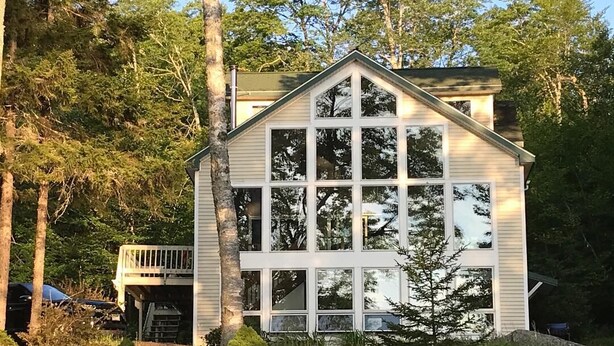 A two-story house with a gabled roof and large windows. - Beautiful lakefront home on Phillips Lake - Near Acadia! (Dedham)