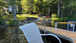 A dock with a chair and a table, a wooden pier, and a river. - Beautiful lakefront home on Phillips Lake - Near Acadia! (Dedham)