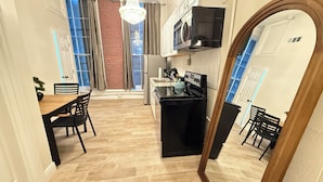 Una cocina moderna con encimera negra, horno integrado y microondas. Hay una zona de comedor con una mesa de madera y sillas negras.