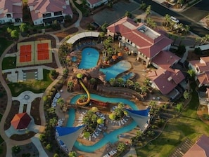 An aerial view of a resort with multiple swimming pools, a water slide, and lounge areas.