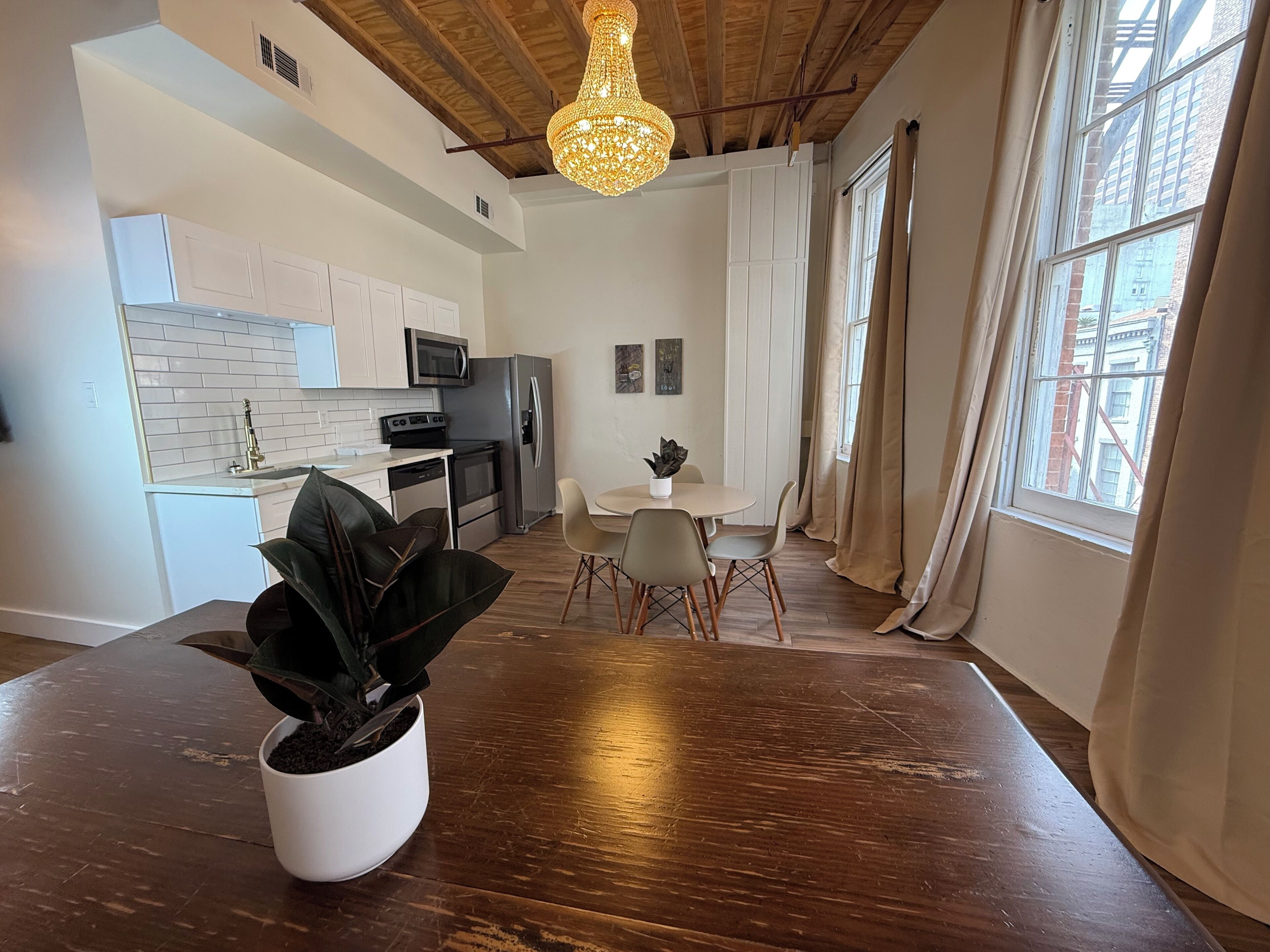 A modern kitchen with white cabinets, stainless steel appliances, and a dining area with a wooden table and chairs.