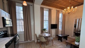 A modern kitchen with a built-in oven, a dining area with a round table and chairs, and a large window with curtains.