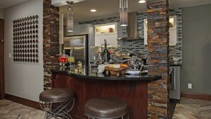 Una cucina moderna con una parete decorata in pietra, elettrodomestici in acciaio inossidabile e un'area bar con sgabelli.