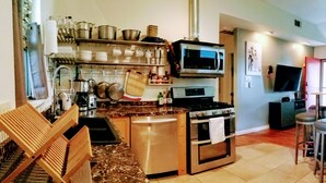 A compact kitchen with a stove, oven, microwave, and various kitchen utensils. - Cottage by Lady Bird Lake and Trail (Austin)