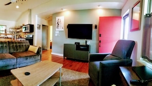A living room with a sofa, a coffee table, a TV, and a fireplace. - Cottage by Lady Bird Lake and Trail (Austin)